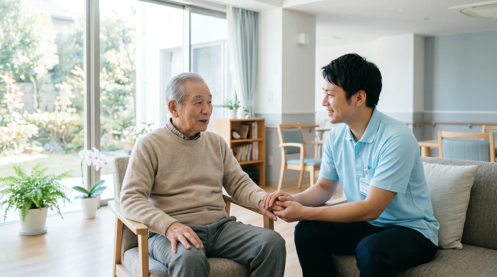 明るいリビングで高齢男性の話を聞く介護スタッフ